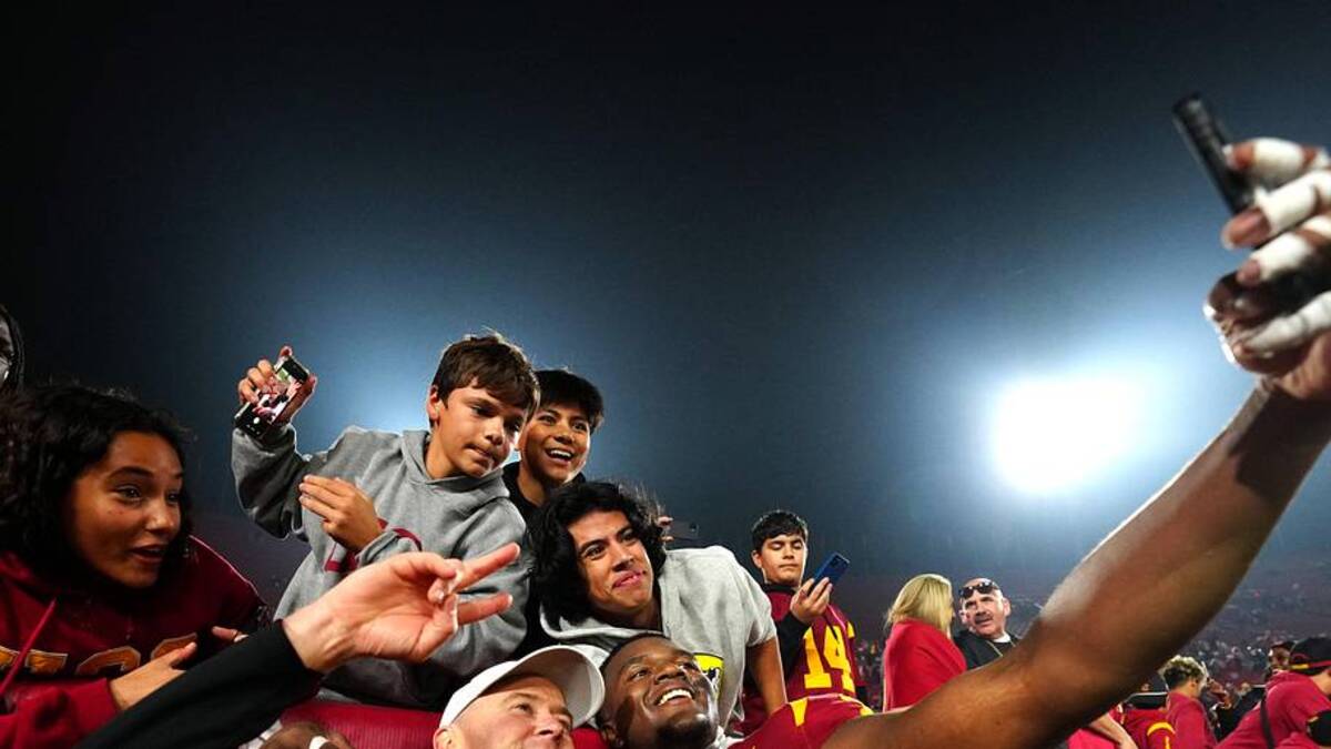  Nov 29, 2025; Los Angeles, California, USA; Southern California Trojans head coach Lincoln Riley (right) and defensive tackle Jahkeem Stewart (4) pose with fans after the game against the UCLA Bruins at United Airlines Field at Los Angeles Memorial Coliseum. Mandatory Credit: Kirby Lee-Imagn Images | Kirby Lee-Imagn Images 