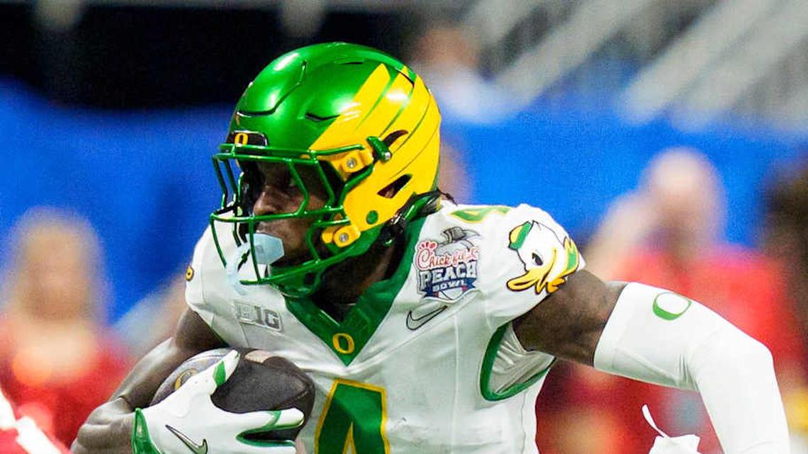  Oregon wide receiver Malik Benson carries the ball under cover from Indiana defensive back Louis Moore as the Oregon Ducks face the Indiana Hoosiers in the Peach Bowl on Jan. 9, 2026, at Mercedes-Benz Stadium in Atlanta, Georgia. | Ben Lonergan/The Register-Guard / USA TODAY NETWORK via Imagn Images 