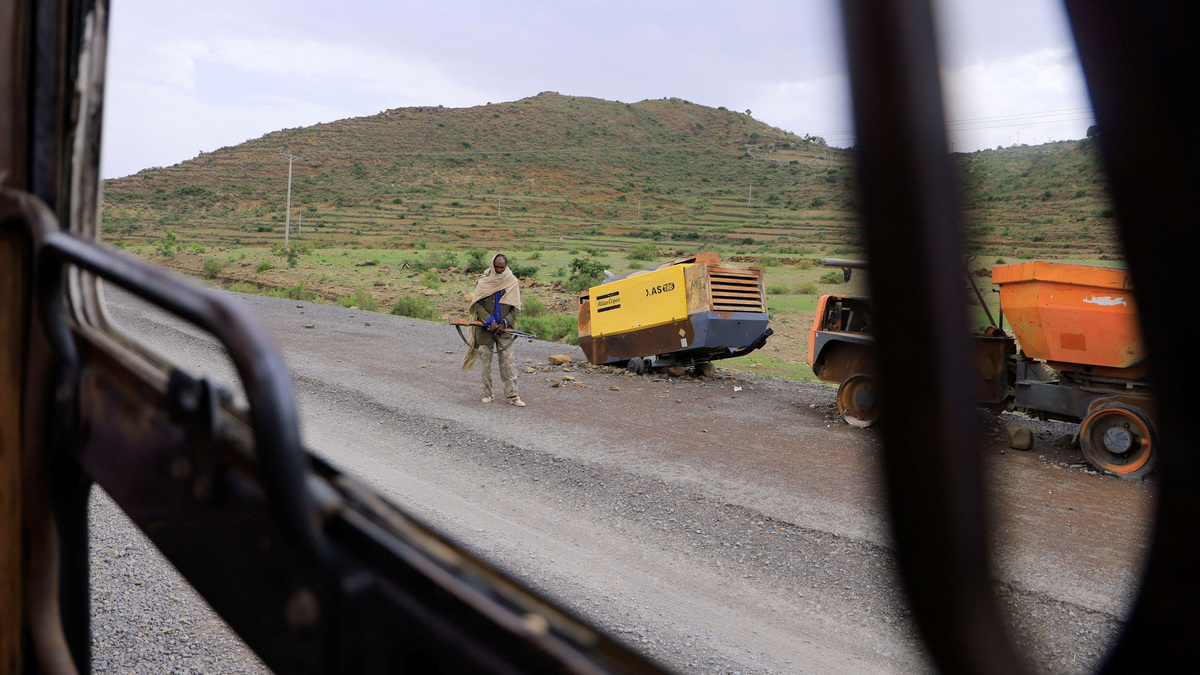 A Tigrayan Militia member stands next to construction machinery destroyed during the fighting between the Tigray People's Liberation Front (TPLF) and Ethiopian National Defence Force (ENDF) allied with Amhara Special Forces and Eritrean Defence Forces (EDF) on the outskirts of Samre, Tigray Region, Ethiopia, June 23, 2023. REUTERS/Tiksa Negeri