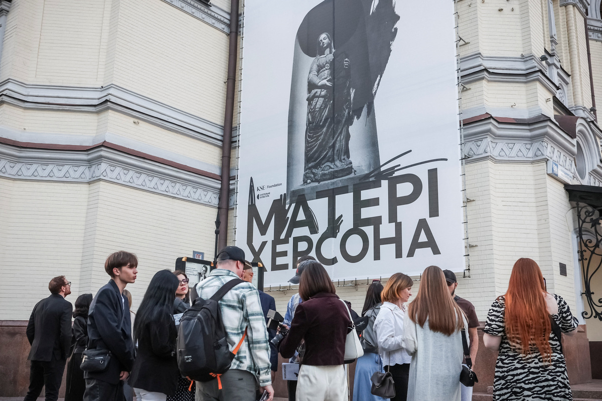 Children abducted by Russia who were later rescued by their relatives and returned to Ukraine stand with family members in front of a banner advertising the contemporary opera "Mothers of Kherson" outside the Taras Shevchenko National Opera and Ballet Theatre, which tells a story based on their families’ experiences, co-commissioned by Metropolitan Opera in New York and the Polish National Opera in Warsaw, amid Russia’s attack on Ukraine, in Kyiv, Ukraine, June 4, 2026. REUTERS/Alina Smutko