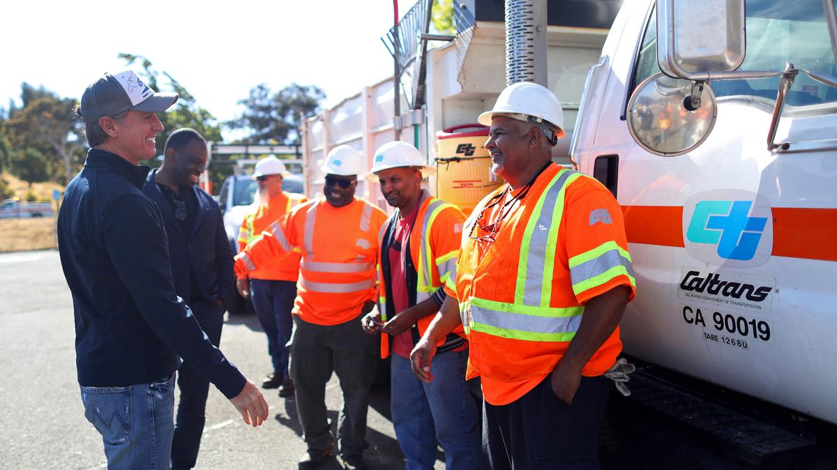 California Gov. Gavin Newsom, left, greets Caltrans workers at a news conference in 2021. Maintenance workers from the International Union of Operating Engineers, some of whom work within Caltrans, have approved a new labor agreement that gives members modest raises over three years.
