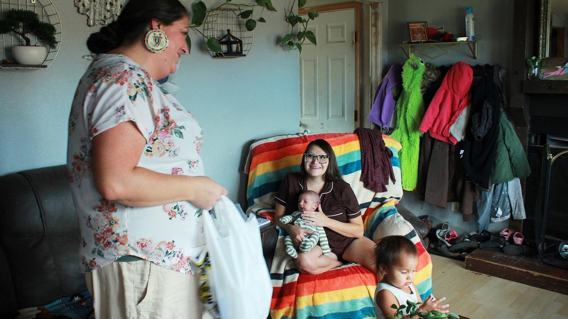 Misty Pipe (left) delivers a care package for one of the women she recently supported through pregnancy, Britney WolfVoice. Pipe offers free doula care outside of her post office job because Lame Deer — her hometown on the Northern Cheyenne Indian Reservation in Montana — is about 100 miles from the closest hospital that delivers babies. (Katheryn Houghton/KFF Health News/TNS)