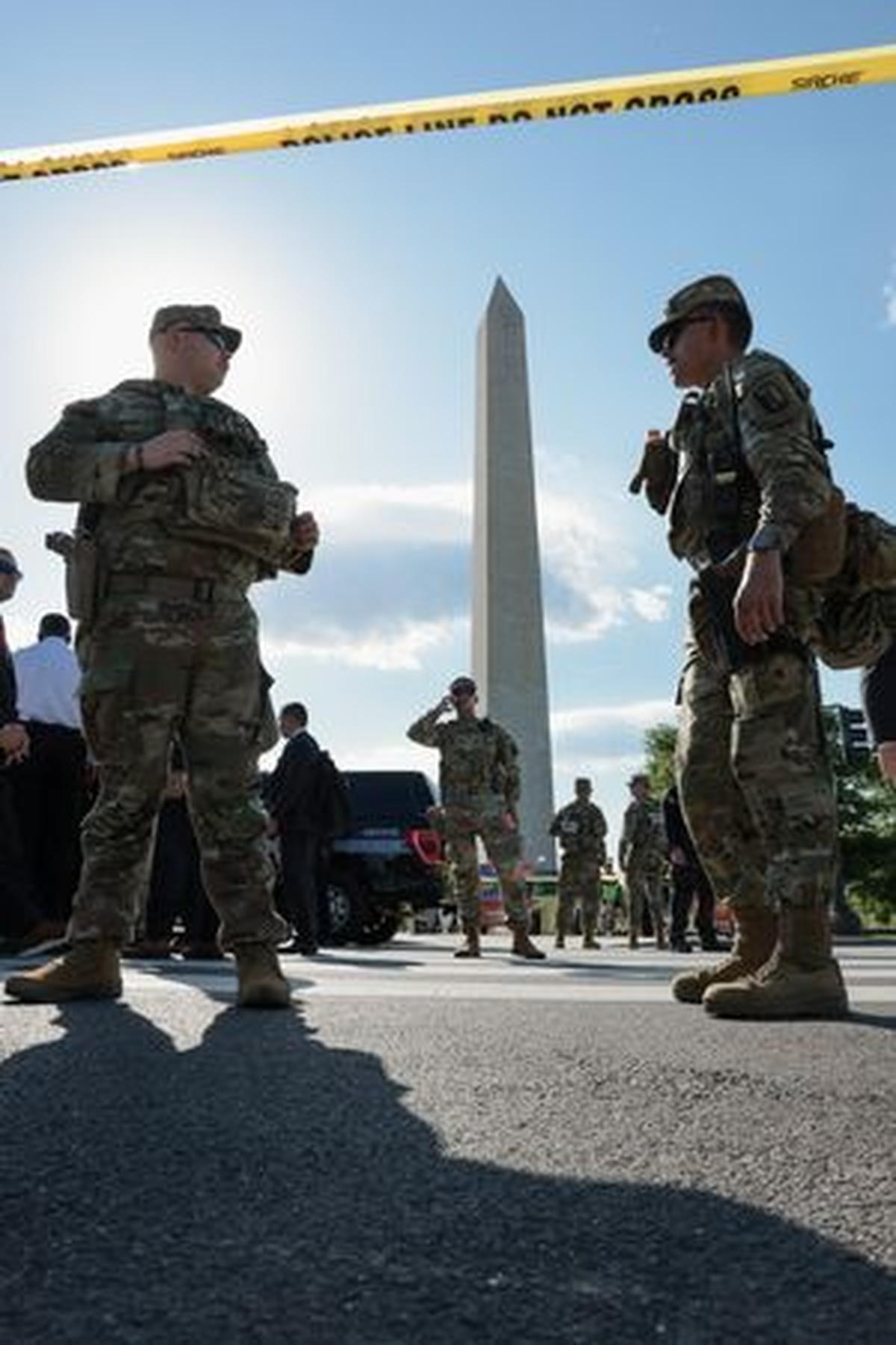 Law enforcement officers stand watch behind a cordon off area at the scene of an officer-involved shooting, with the Washington Monument in the background, in Washington, D.C., U.S., May 4, 2026. REUTERS/Jonathan Ernst