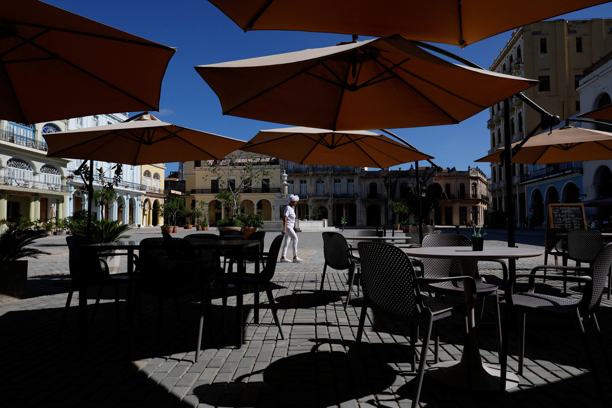 A santera, a priestess in the Afro-Cuban religion Santeria, walks past an empty cafe at the Old Square, one of the most popular tourist spots in Old Havana, as U.S. sanctions have led most major tourism and travel companies to leave the island or drastically scale back their operations, in Havana, Cuba June 8, 2026. REUTERS/Norlys Perez