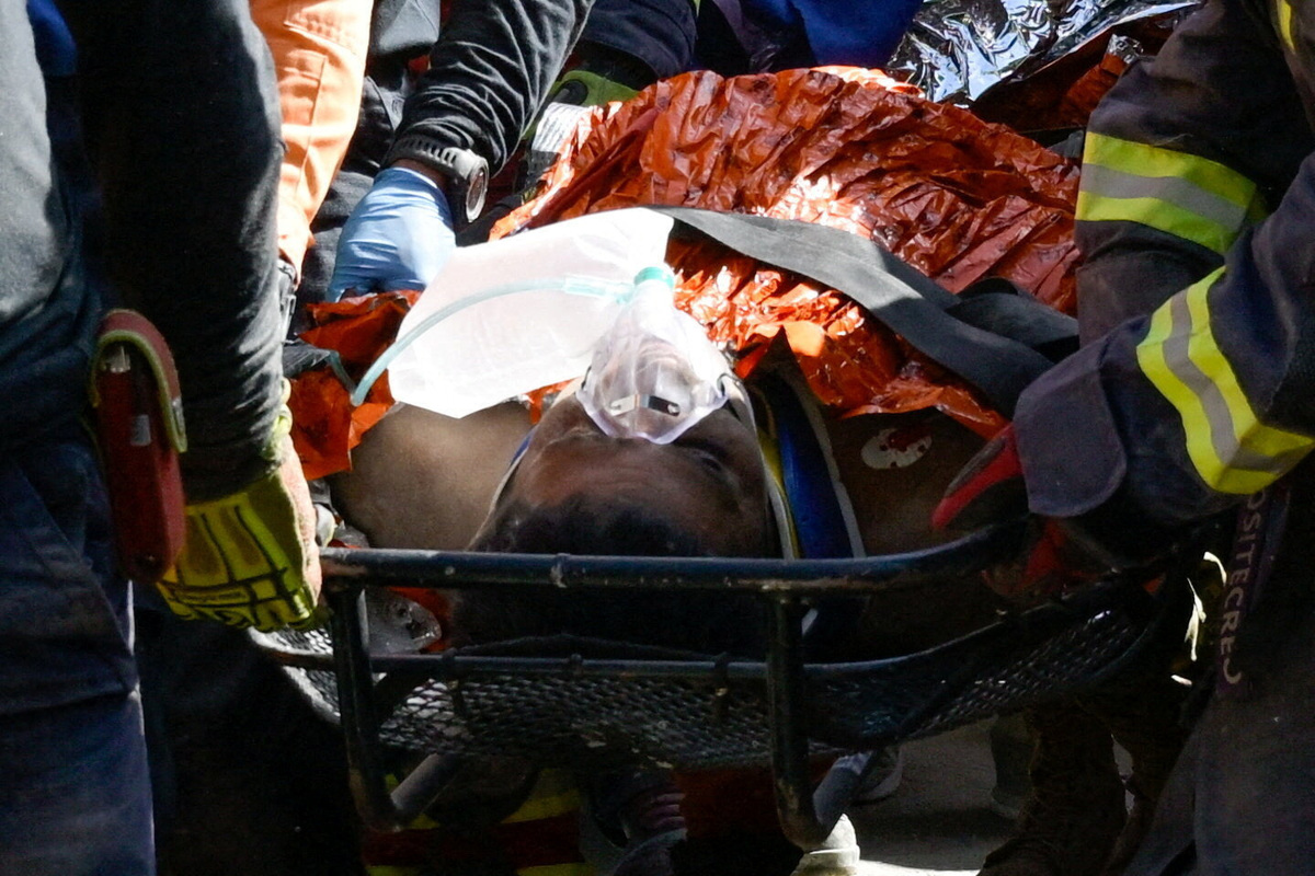 Rescue workers transport survivor Hernan Alberto Gil, who was trapped for over a week at a collapsed mall following the June 24 earthquakes, in La Guaira, Venezuela, on Thursday.