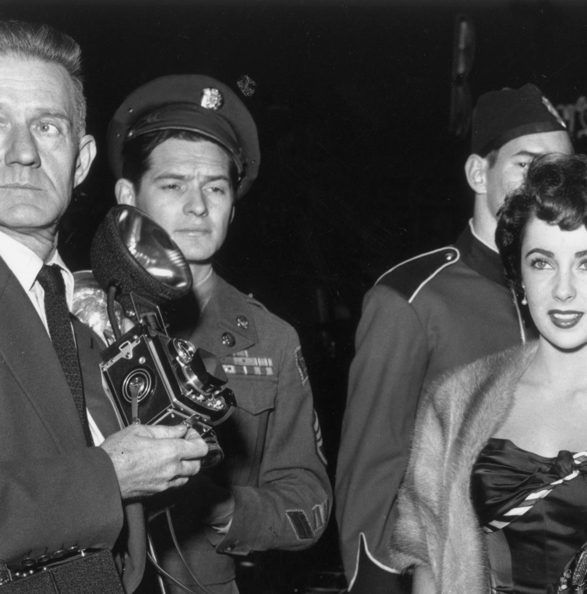 Elizabeth Taylor, wearing an evening gown with a fur coat, arrives at a film premiere with American actor Richard Long (1927 – 1974), wearing a tuxedoM. Garrett/Murray Garrett/Getty Images