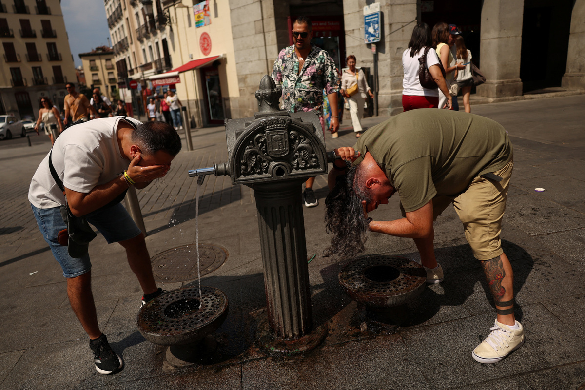 Men cool off at a water fountain during a heatwave in Madrid, Spain, July 7, 2026. REUTERS/Susana Vera