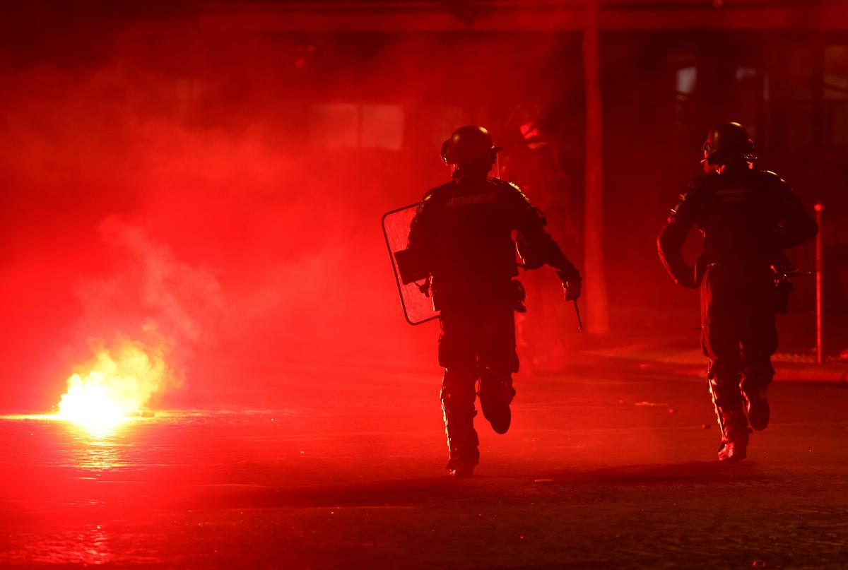 Soccer Football - UEFA Champions League -  Paris St Germain fans celebrate winning the UEFA Champions League - Paris, France - May 31, 2026 Police officers protect themselves from a flare after Paris St Germain won the UEFA Champions League REUTERS/Abdul Saboor