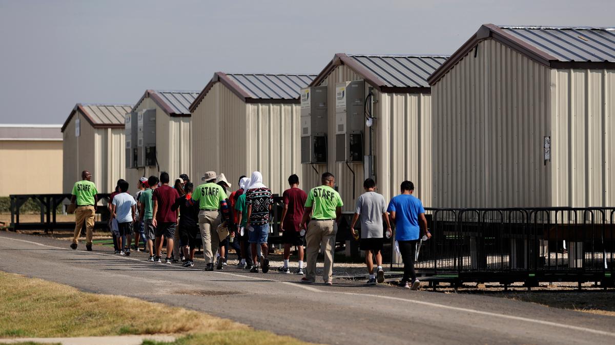 En esta fotografía del 9 de julio de 2019, unos miembros del personal escoltan a unos menores a una clase en un centro de detención para niños migrantes del gobierno de Estados Unidos en Carrizo Springs, Texas. (AP Foto/Eric Gay)