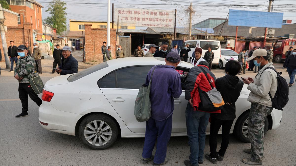 FILE PHOTO: People gather by a car to ask for jobs, on a street where labourers and migrant workers usually gather for odd jobs, near the border with Hebei province, in Beijing, China April 13, 2022. REUTERS/Tingshu Wang/File Photo