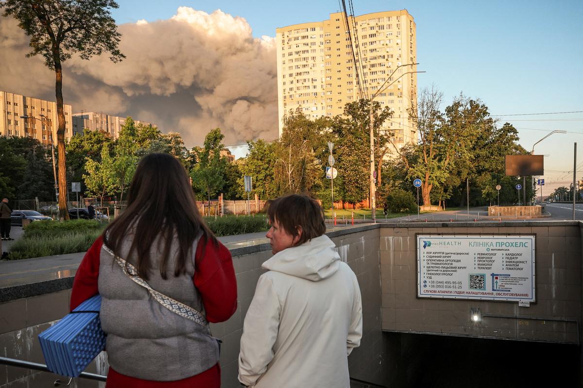 People walk from a metro station, where they took shelter during an overnight Russian missile and drone strike, as smoke rises from the outskirts of the city, amid Russia's attack on Ukraine, in Kyiv, Ukraine May 24, 2026. REUTERS/Alina Smutko