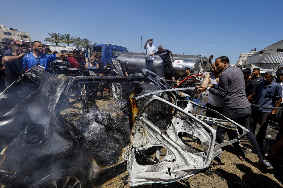 Palestinians pour water on a destroyed vehicle at the site of an Israeli strike, in Deir al-Balah, in the central Gaza Strip, June 2, 2026. REUTERS/Mahmoud Issa