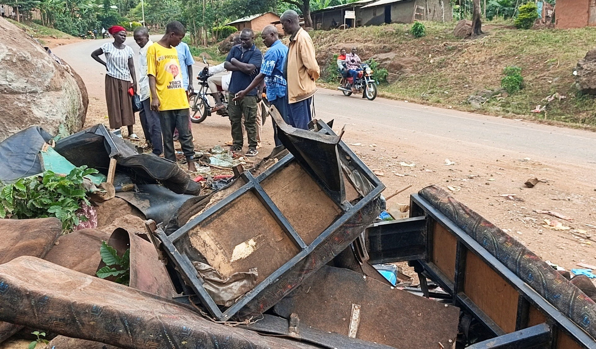 People gather near the wreckage of a bus, owned by King David Junior School, on the shoulder of the road following an accident that killed schoolchildren on the way back from an educational visit to Sipi Falls; at Chekwatit village in Kapchorwa district, Uganda, July 17, 2026. Picture taken with a mobile phone. REUTERS/Stringer