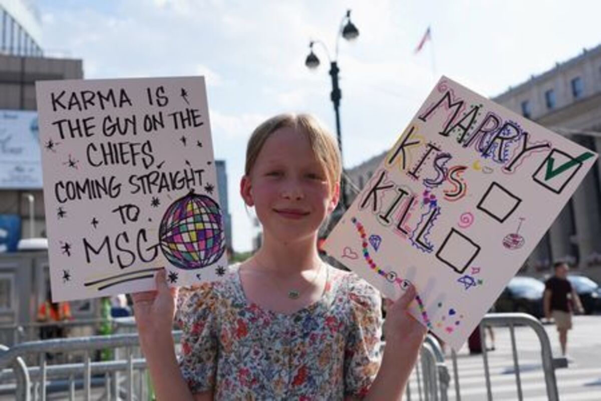 A child holds placards near Madison Square Garden, the venue for the reported wedding celebrations of singer Taylor Swift and National Football League (NFL) player Travis Kelce, in New York, U.S., July 3, 2026.  REUTERS/Christian Monterrosa