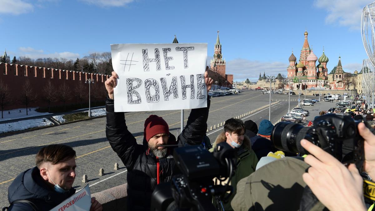 ARCHIVO - Un hombre sostiene un cartel que dice “No a la guerra” mientras la gente deposita flores cerca del sitio donde el líder de la oposición rusa Boris Nemtsov fue baleado, con el Muro del Kremlin, a la izquierda, la Torre Spaskaya, al centro, y San Basilio al fondo. de fondo, en Moscú, Rusia, el domingo 27 de febrero de 2022. (Foto AP, archivo)