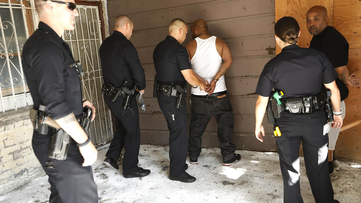 Los Angeles police officers, with the 77th Police Department Gang Unit, arrest two men suspected of operating an unlicensed marijuana shop in South Los Angeles on July 25, 2019. (Genaro Molina/Los Angeles Times/TNS)