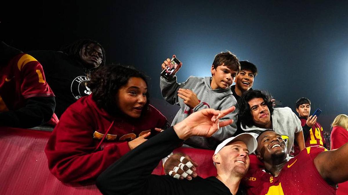  Nov 29, 2025; Los Angeles, California, USA; Southern California Trojans head coach Lincoln Riley (right) and defensive tackle Jahkeem Stewart (4) pose with fans after the game against the UCLA Bruins at United Airlines Field at Los Angeles Memorial Coliseum. Mandatory Credit: Kirby Lee-Imagn Images | Kirby Lee-Imagn Images 