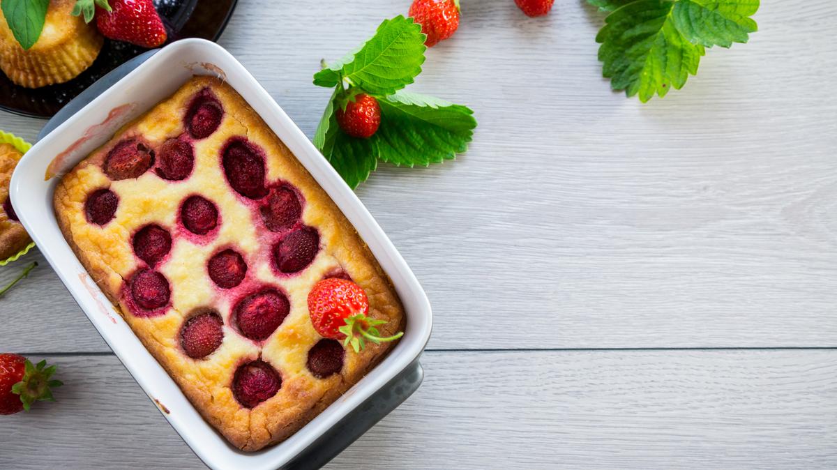 Sweet cottage cheese casserole with strawberry filling, in a plate on a wooden table.