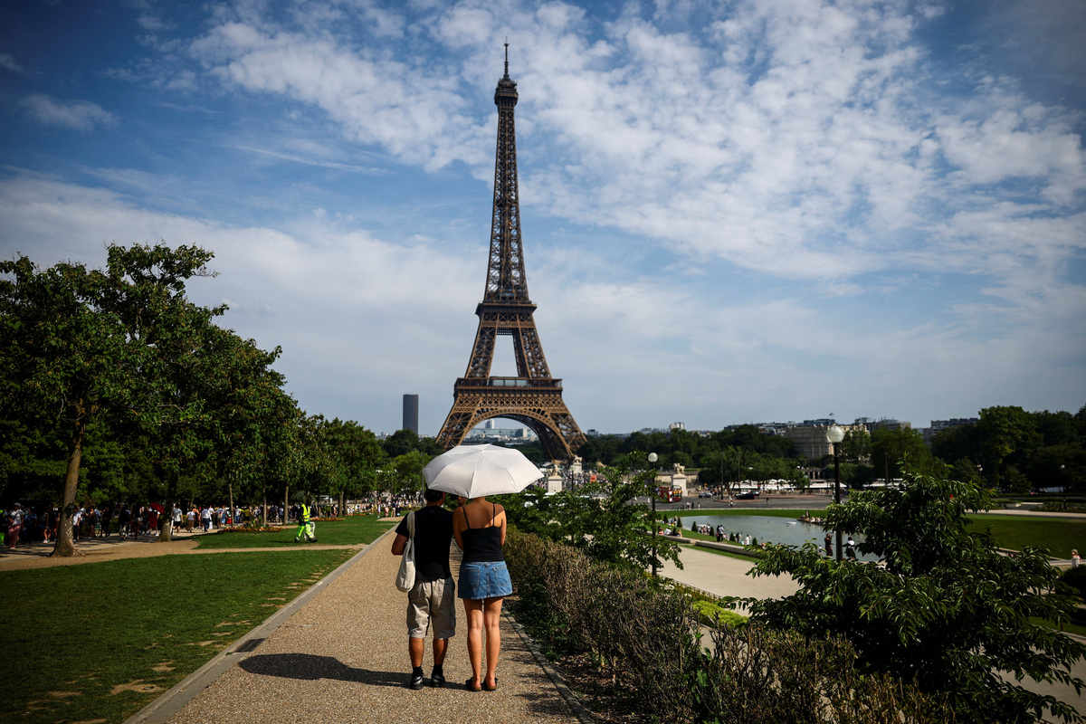 People protect themselves from the sun under an umbrella near the Eiffel Tower as temperatures rise in Paris during a second heatwave affecting a large part of France, June 20, 2026. REUTERS/Sarah Meyssonnier