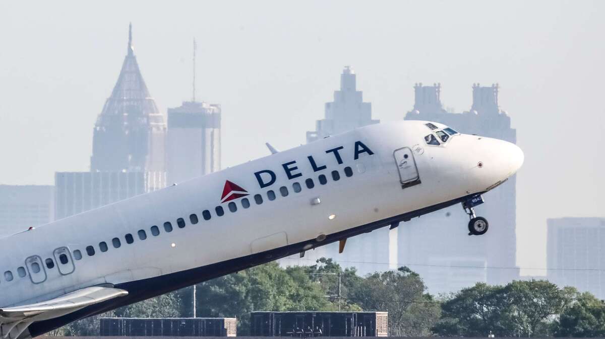 A Delta Air Lines jet takes off with the skyline of Atlanta behind it on April 27, 2021. (John Spink/John.Spink@ajc.com)