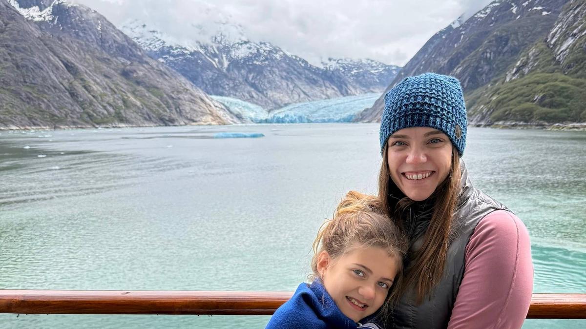 A mother and daughter pose for a photo in front of Dawes Glacier while on a cruise ship sailing in Endicott Arm, Alaska. 