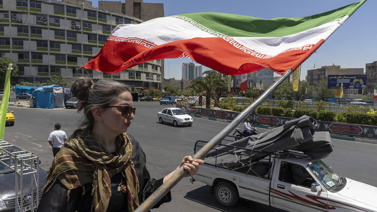 A woman waves an Iranian flag on June 15, 2026, in Tehran, Iran. According to reports, the U.S. and Iran have signed a preliminary agreement to end the war and open the Strait of Hormuz. (Majid Saeedi/Getty Images/TNS)