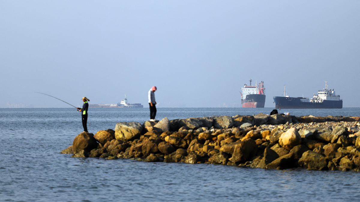 In this picture obtained from Iran's ISNA news agency on June 8, 2026, residents fish from the shore as cargo and commercial vessels lie at anchor in the Strait of Hormuz off Bandar Abbas on June 8, 2026. (Amirhossein Khorgooei/ISNA/AFP/Getty Images/TNS)