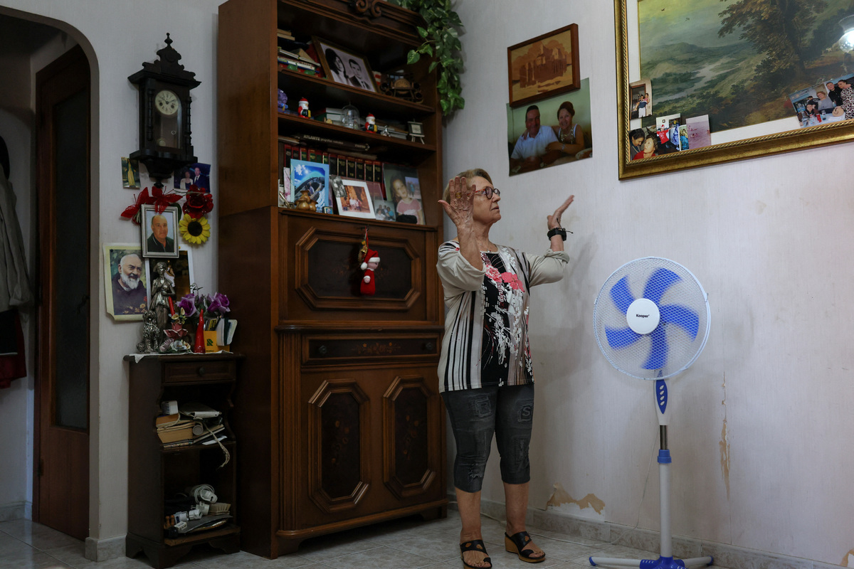 Dina Gazzella, 85, wearing an electronic bracelet that monitors her heart rate and sleep patterns, allows her to call for help in an emergency, and enables a team of social workers to monitor her remotely, stands near a fan, in Rome, Italy, June 26, 2026. The device is part of a support scheme for the elderly introduced last year by Rome's municipality, which local authorities describe as an important preventive healthcare tool, particularly during the Europe-wide heatwave that has pushed temperatures in Rome above 30 degrees Celsius. REUTERS/Yara Nardi