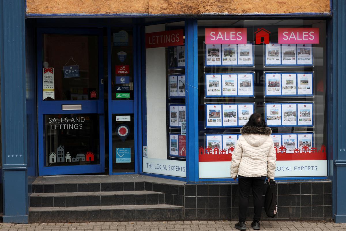 A woman watches a real estate office offert ahead of the Makerfield by-election, triggered by Labour MP Josh Simons, who resigned as a minister in March, in Ashton-in-Makerfield, Britain, May 20, 2026. REUTERS/Temilade Adelaja