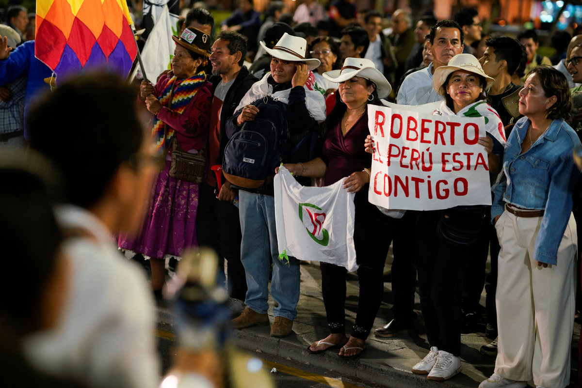 A woman holds a poster that reads, "Roberto, Peru is with you" as supporters of left-wing presidential candidate Roberto Sanchez gather after Sanchez took a slim lead over conservative Keiko Fujimori in Peru's presidential race as official vote-counting continued into a second day, in Lima, Peru, June 8, 2026. REUTERS/Leslie Moreno