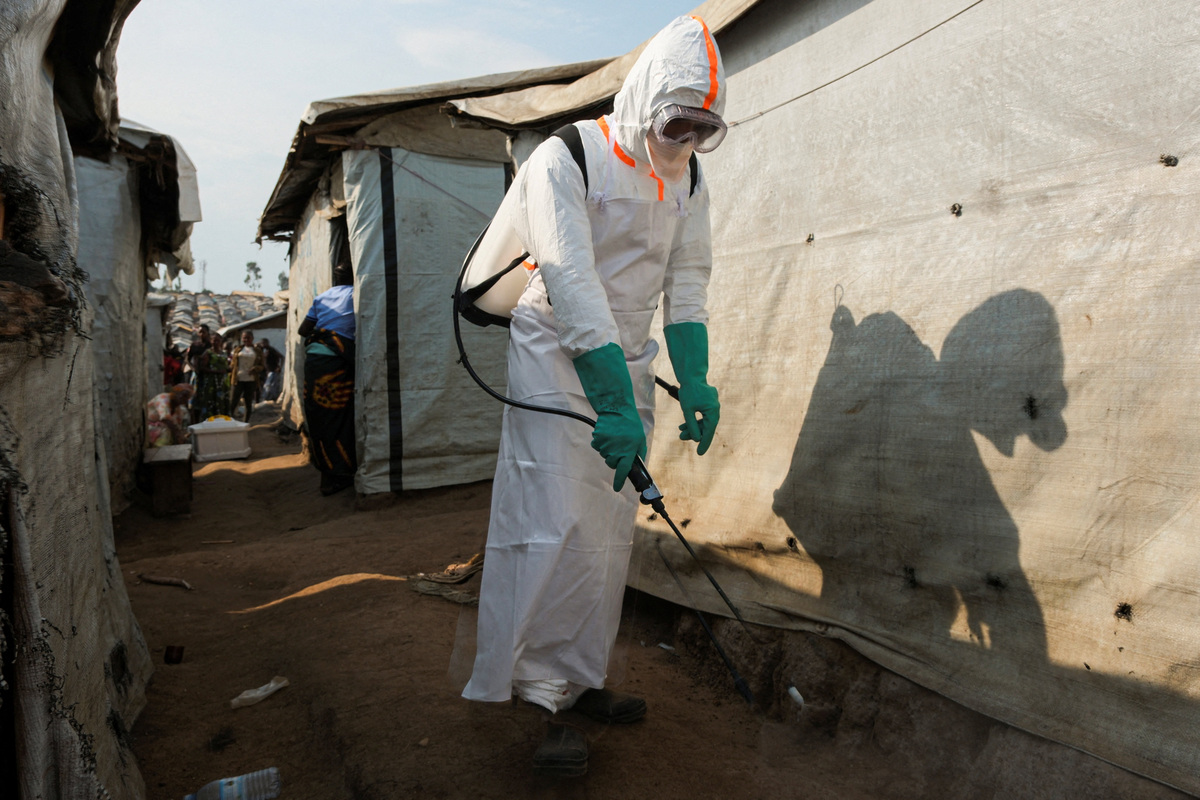 A health worker in full personal protective equipment (PPE) disinfects an area while preparing for the burial of suspected Ebola victims at the Kigonze displaced persons camp in Bunia, eastern Democratic Republic of Congo, on June 18, 2026, one month after the outbreak was declared. REUTERS/Gradel Muyisa Mumbere