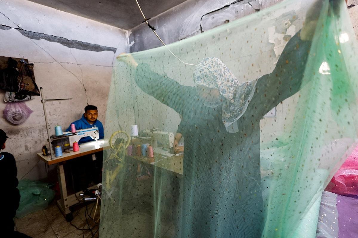 A Palestinian woman works at a sewing shop producing and repairing wedding dresses and children’s gowns, as families in Gaza turn to reused garments amid soaring prices and shortages caused by the war, in Khan Younis in the southern Gaza Strip, May 10, 2026. REUTERS/Mahmoud Issa