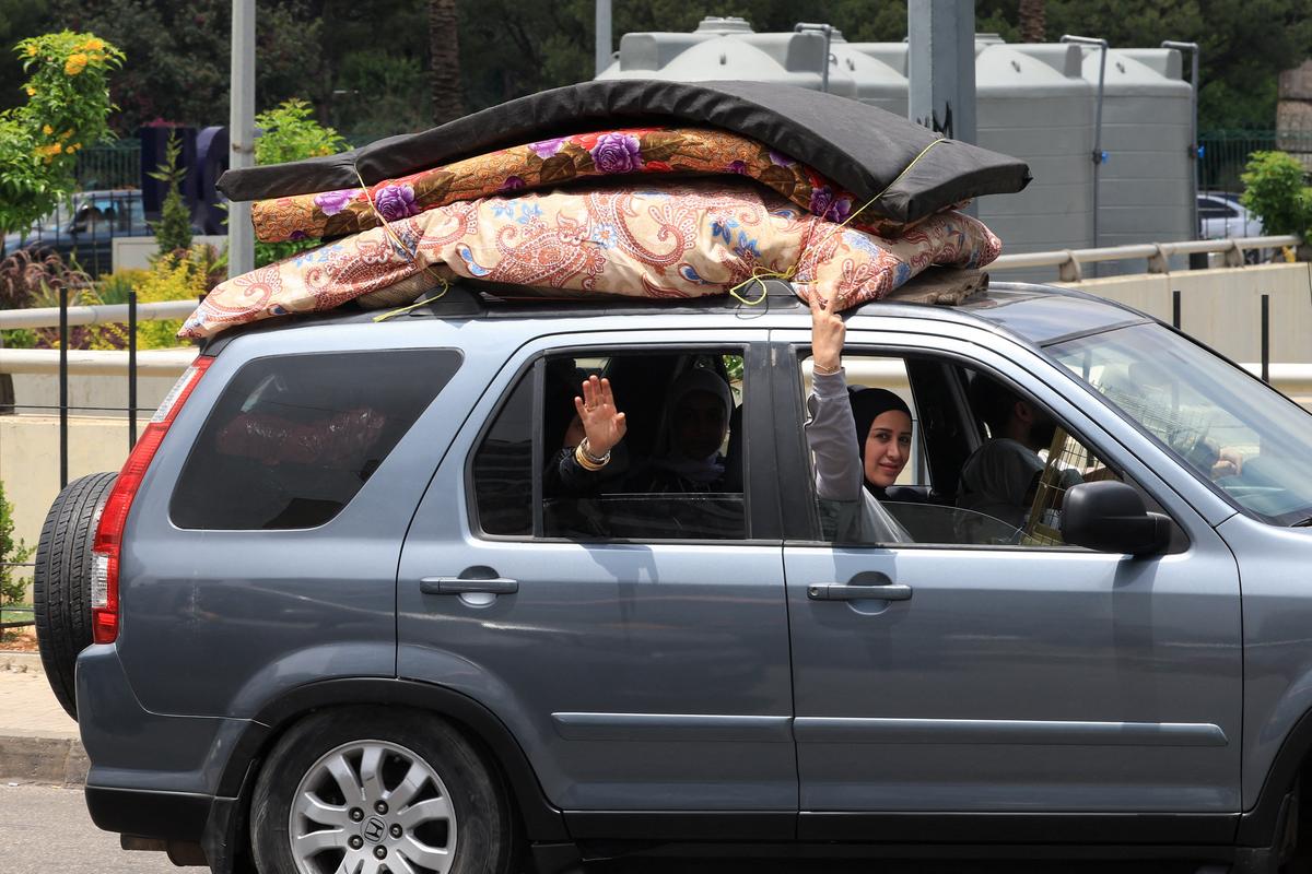 A woman gestures from a car while people make their way as they flee the southern suburbs of Beirut, after Israeli Prime Minister Benjamin Netanyahu ordered the military to attack targets in the suburbs, Lebanon, June 1, 2026. REUTERS/Mohamed Azakir