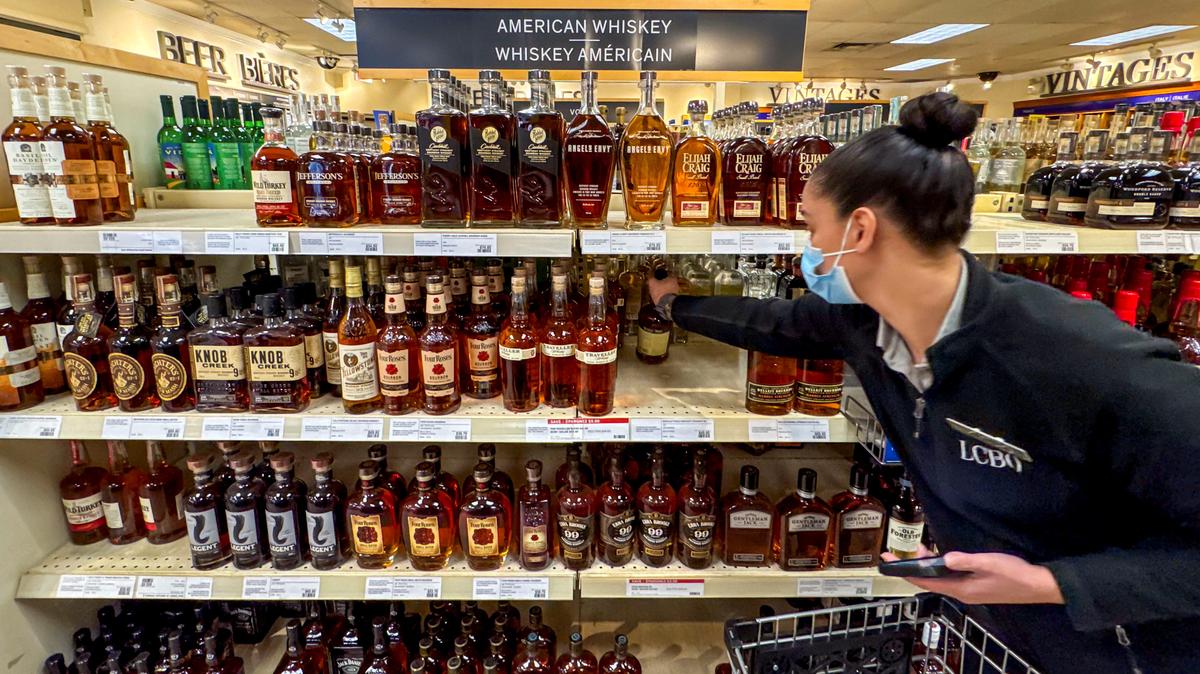 A worker places bottles of American whiskey into a shopping cart to fill an order for a restaurant, at a Liquor Control Board of Ontario (LCBO) store in Hamilton, Ontario, Canada February 2, 2025.  REUTERS/Carlos Osorio