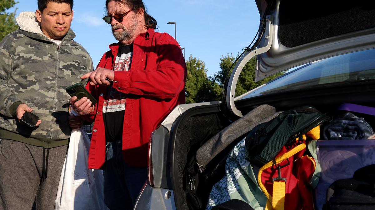 Larry Gephart, right, assists Jose Angel Miranda, of Nicaragua, who was released from the North Lake Processing Center in Baldwin, Michigan, with a phone call from an attorney outside the facility on May 14, 2026. (Antonio Perez/Chicago Tribune/TNS)