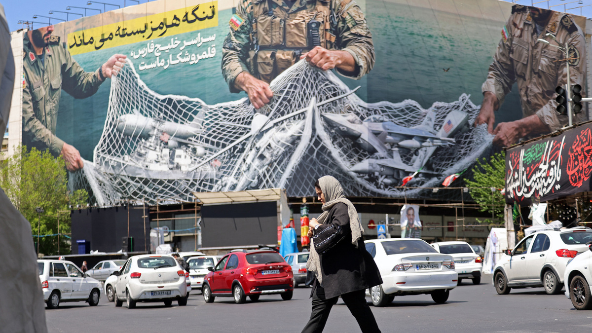 A woman walks past a giant billboard reading "The Strait of Hormuz remains closed" at the Revolution Square in Tehran, Iran, on April 12, 2026. (Atta Kenare/AFP/Getty Images/TNS)