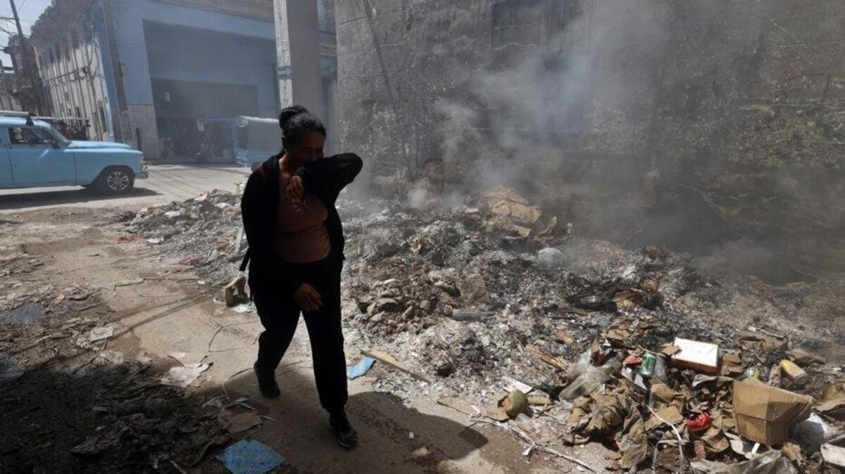 A man shields himself from smoke rising out of a trash fire in Havana in late May. Photo by Ernesto Mastrascusa/EPA