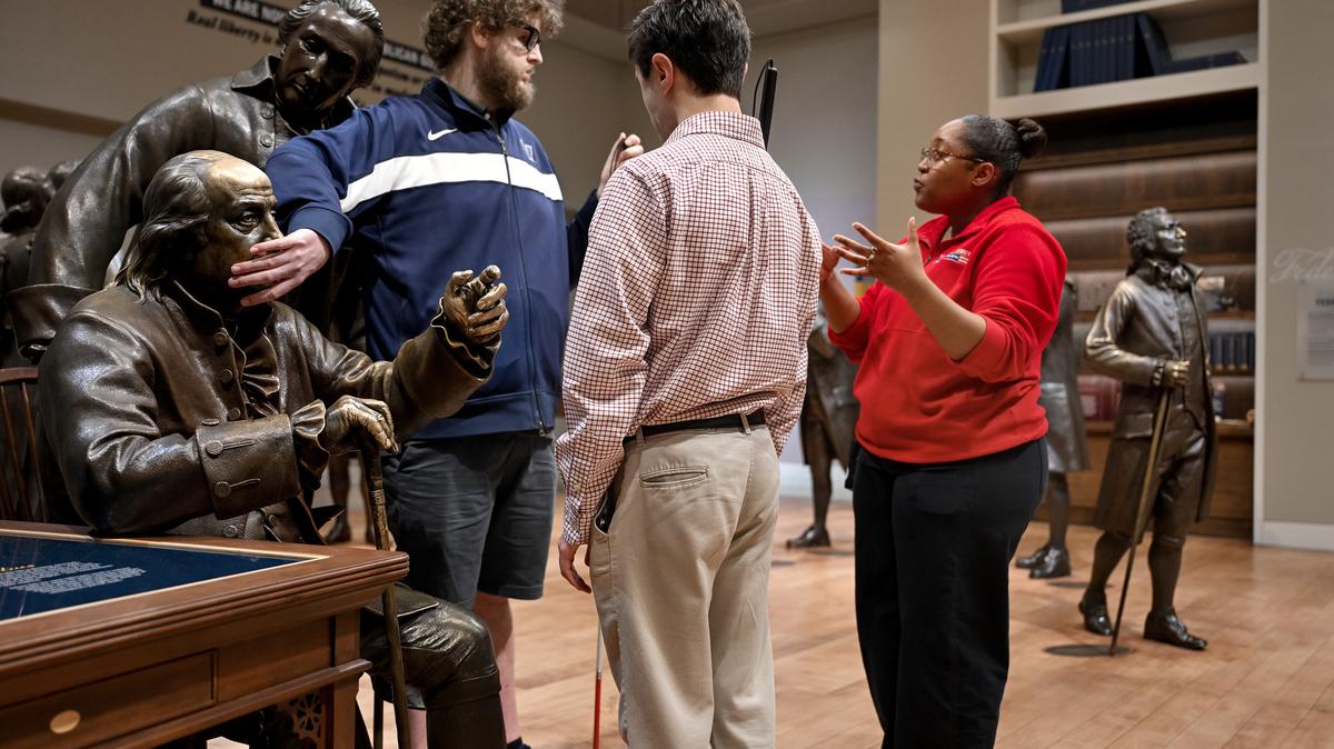 Jeff Boudwin (front) examines the face of Benjamin Franklin as museum educator Aria Springfield discusses his role at the Constitutional Convention. (Tom Gralish/The Philadelphia Inquirer/TNS)