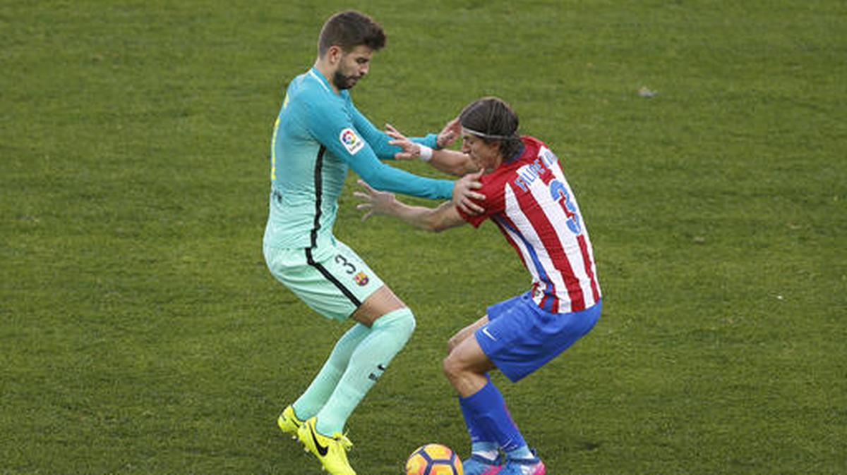 El jugador de Barcelona Gerard Piqué (izq.) lucha por la pelota con Filipe Luis, del Atlético de Madrid, en un partido de la liga española, celebrado el 26 de febrero del 2017.