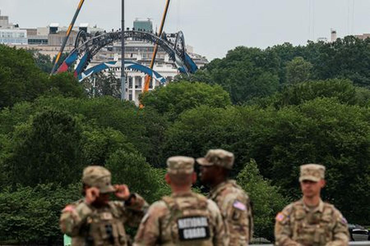 Members of the National Guard stand at the base of the Washington Monument, as construction on a temporary arena that will host the UFC Freedom 250 fight card in June on the South Lawn of the White House appears in the distance, in Washington, D.C., U.S., May 27, 2026. REUTERS/Kylie Cooper