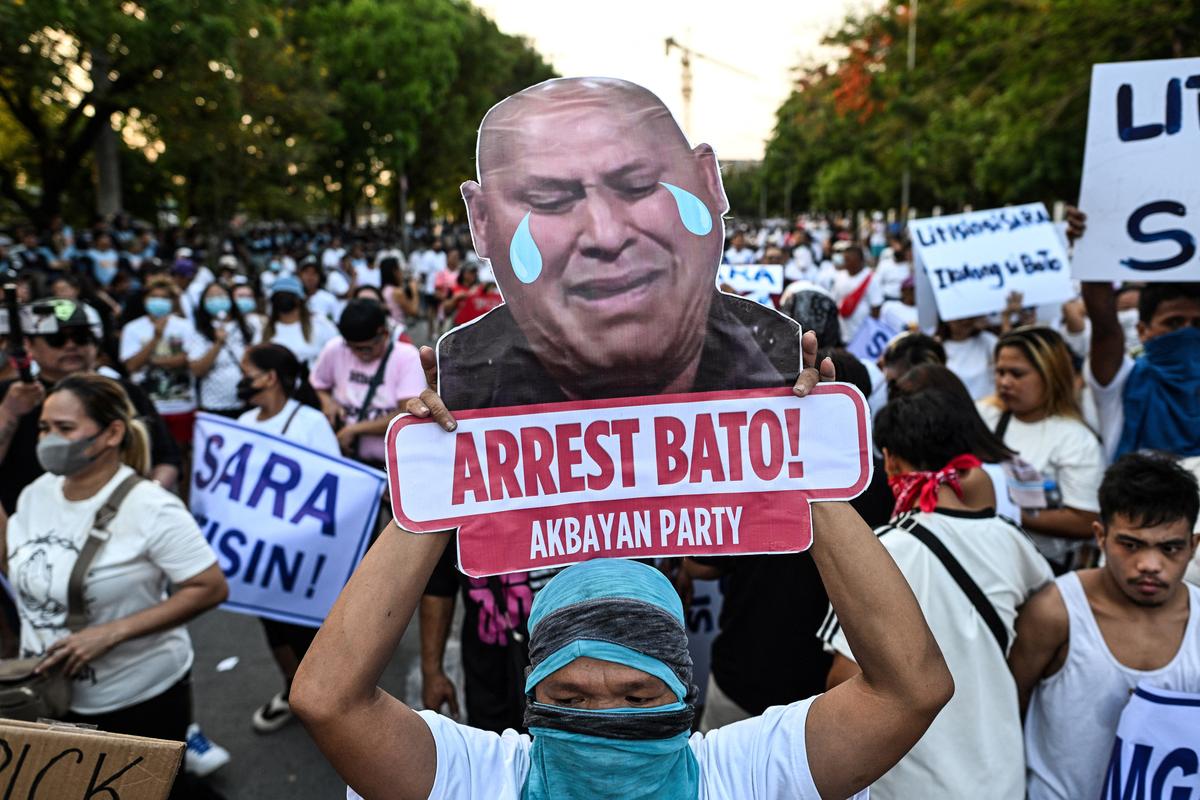 An activist displays a sign with a slogan calling for the arrest of Philippine Senator Ronald "Bato" dela Rosa's, during a protest outside the Philippine Senate, which holds dela Rosa, the chief enforcer of former president Rodrigo Duterte's drug war, in protective custody amid an International Criminal Court warrant, in Pasay City, Metro Manila, Philippines, May 13, 2026. REUTERS/Noel Celis