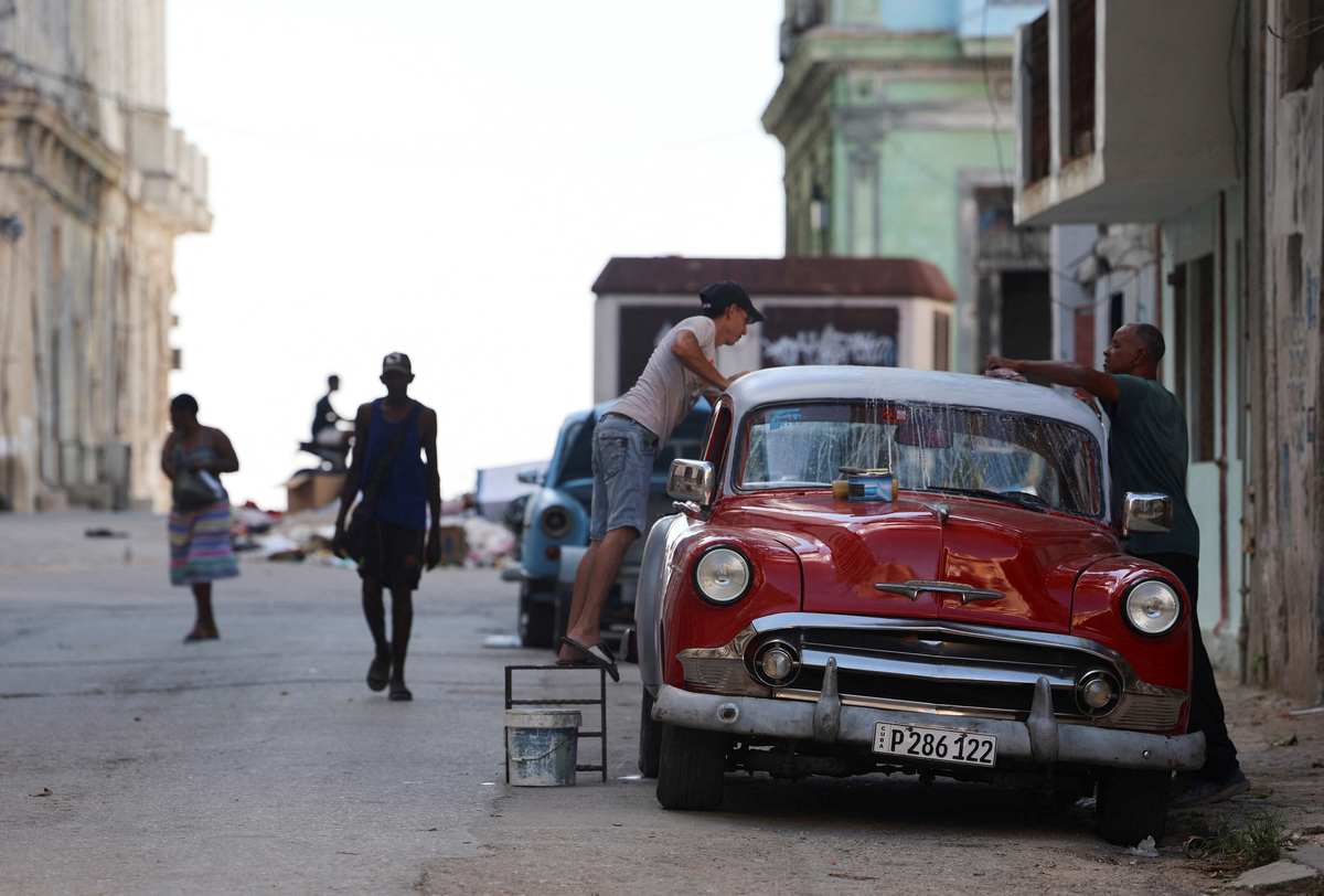 Men wash a vintage car on a street before the Cuban government presents far-reaching economic measures that could mark the most significant shift toward a market economy since the 1959 revolution, in Havana, Cuba June 17, 2026. REUTERS/Norlys Perez
