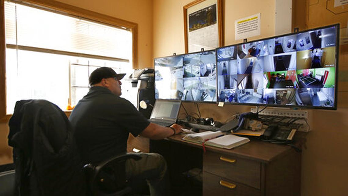 In this photo taken Wednesday, Feb. 20, 2019, California Correctional Officer Alejandro Martinez monitors surveillance cameras at the Male Community Re-entry Program an alternative custody unit in Oroville, Calif.