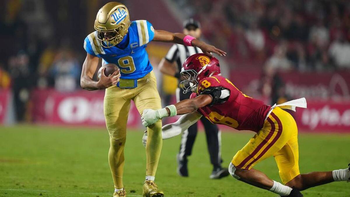  Nov 29, 2025; Los Angeles, California, USA; UCLA Bruins quarterback Nico Iamaleava (9) is tackled by Southern California Trojans linebacker Eric Gentry (18) in the second half at United Airlines Field at Los Angeles Memorial Coliseum. Mandatory Credit: Kirby Lee-Imagn Images | Kirby Lee-Imagn Images 