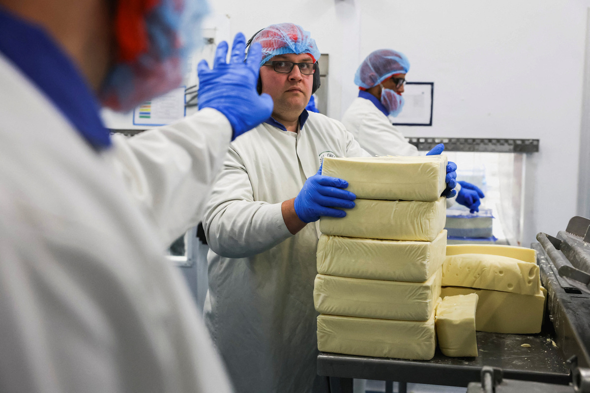 A worker stacks blocks of cheese on a production line at the Bridge Cheese factory in Telford, Britain, June 10, 2026. REUTERS/Temilade Adelaja