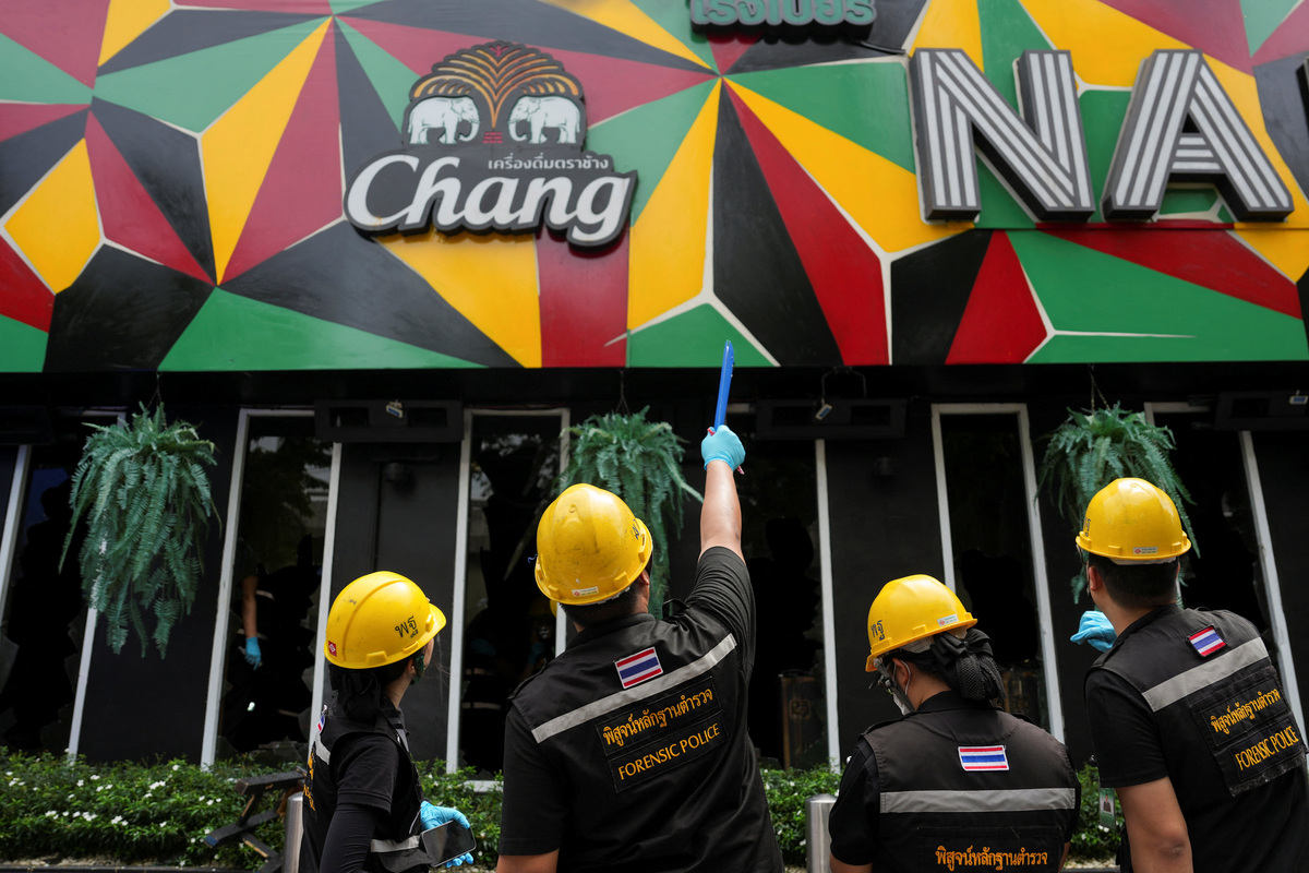 Forensic police officials inspect the site of a deadly fire at a pub in Bangkok, Thailand, July 13, 2026. REUTERS/Arnun Chonmahatrakool