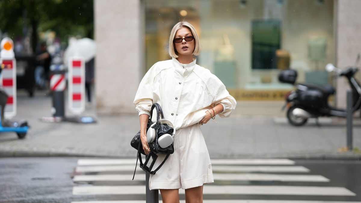 FRANKFURT AM MAIN, GERMANY - JUNE 3: Laura Wittek is seen wearing a white cotton oversized cropped jacket with a high collar, button front closure and gathered sleeves from Laura Wittek x Na-kd; white cotton shorts with a straight silhouette and elastic waist detail from Massimo Dutti; a black leather compact shoulder bag with a curved silhouette and silver tone hardware from Balenciaga; silver bracelets and rings; rectangular acetate sunglasses with dark tinted lenses from Corlin Eyewear; silver Apple headphones; her blonde hair is worn in a sleek bob with a center part; with natural make up on June 3, 2026 in Frankfurt am Main, Germany. (Photo by Moritz Scholz/Getty Images)