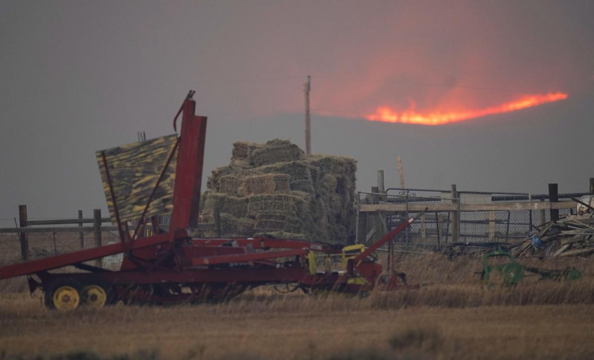  Bales of hay and implements sit on a farm as flames illuminate a nearby ridge as a wildfire burns, on October 22, 2020, near Granby, Colorado. (AP Photo/David Zalubowski) 