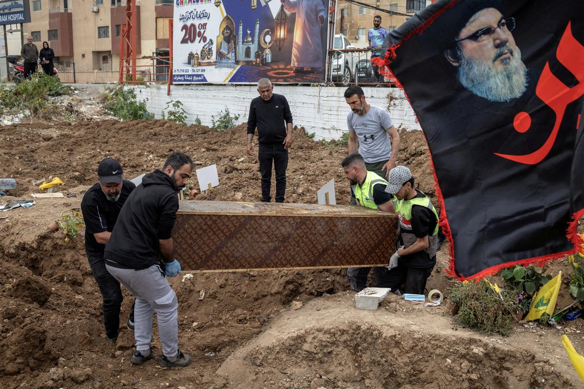 FILE PHOTO: Workers remove a coffin with a body from temporary graves and prepare for transport for a funeral ceremony of four Hezbollah fighters and two civilians, amid a temporary ceasefire between Lebanon and Israel, in Tyre, southern Lebanon, April 26, 2026. REUTERS/Marko Djurica/File Photo