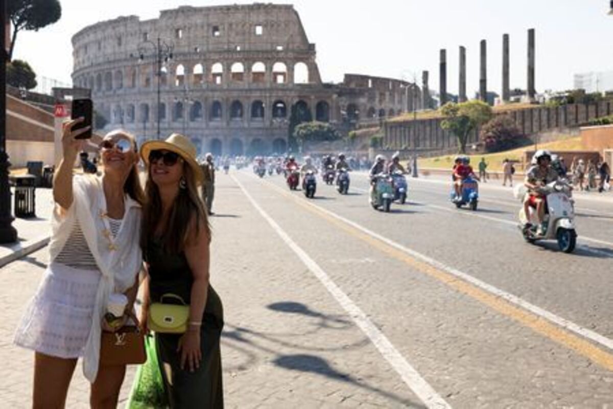 People take a selfie as Vespa riders drive past the Colosseum the last day of “Vespa Roma 2026 - 80 Years of an Icon”, a four-day global gathering marking the 80th anniversary of the iconic Italian scooter brand, in Rome, Italy, June 27, 2026. REUTERS/Remo Casilli